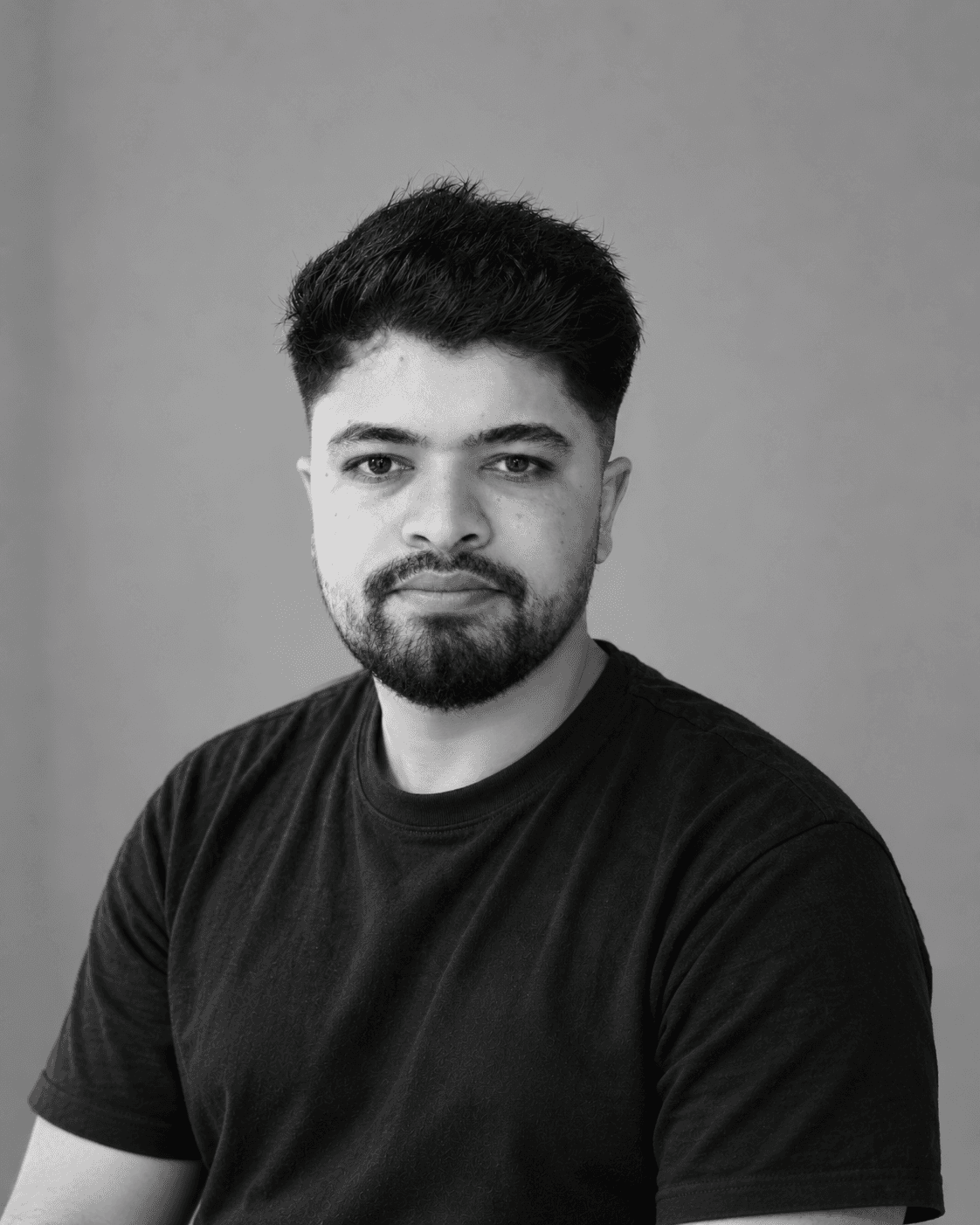 Black-and-white portrait of Rupak Sapkota in a dark T-shirt, looking at the camera.